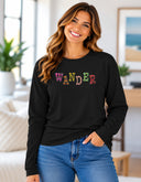 Woman wearing black Wander long sleeve tee with colorful floral lettering created from Victoria Island flower photography