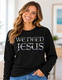 Woman wearing white We Need Jesus long sleeve black tee featuring Aruba sunrise-filled lettering