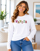 Woman wearing white Wander long sleeve tee with colorful floral lettering created from Victoria Island flower photography
