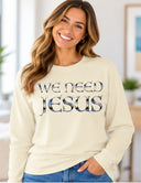 Woman wearing white We Need Jesus long sleeve butter tee featuring Aruba sunrise-filled lettering