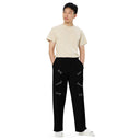Front view of male model in black unisex wide-leg pants with tonal words ‘Sing, Dance, Pray, Laugh, Love, LIVE’ scattered across legs